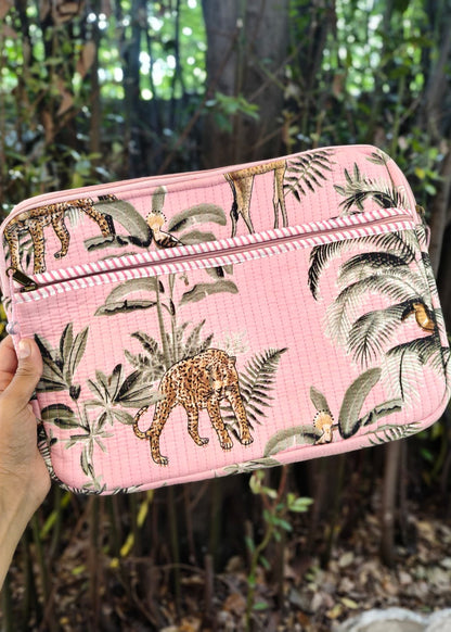 Pink pouch with animal and plant pattern held in front of a forest background