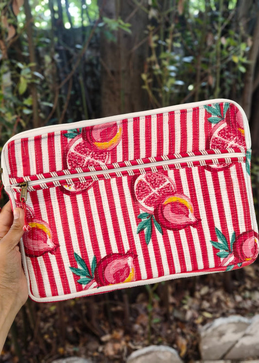 Red and white striped pouch with pomegranate design held in front of a natural background